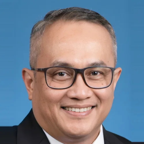 Pas foto pria berkacamata berjas gelap dengan latar biru, foto referensi yang dikirim pelanggan untuk dibuatkan karikatur