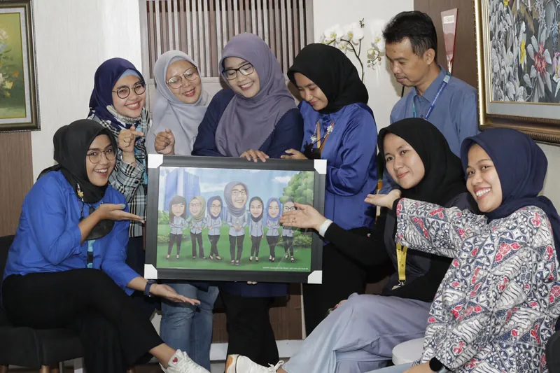 Sekelompok perempuan duduk berdekatan memegang karikatur kelompok berbingkai di ruang kerja.
