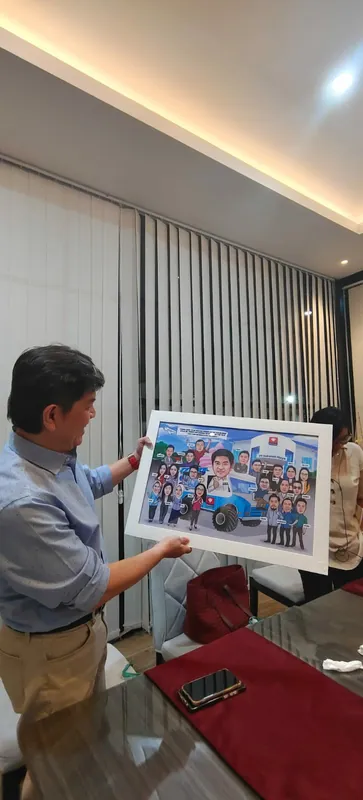 Seorang pria memperlihatkan karikatur kelompok berbingkai kepada rekannya di ruang rapat.