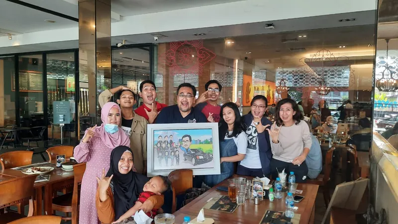 Sekelompok rekan kerja berkumpul di kafe memegang karikatur kelompok berbingkai.