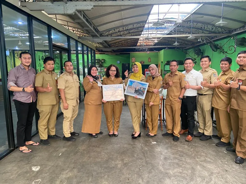 Pegawai berseragam dinas berbaris memegang karikatur kelompok berbingkai di ruang kantor.