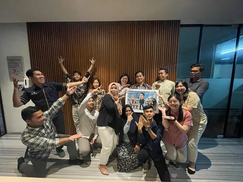 Rekan kerja mengangkat tangan merayakan penyerahan karikatur kelompok berbingkai di kantor.