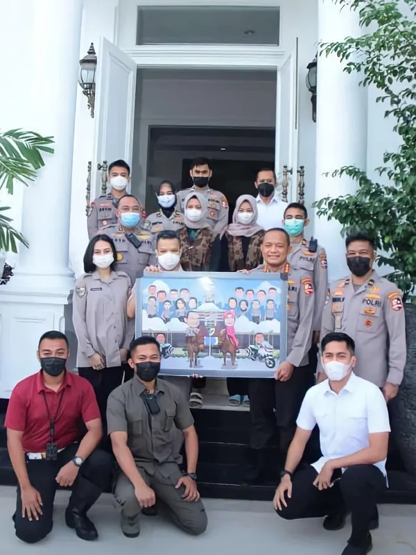 Anggota kepolisian berfoto bersama memegang karikatur kelompok berbingkai.