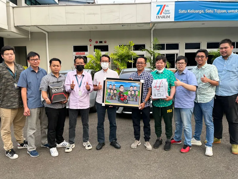 Rekan kerja berbaris di halaman kantor memegang karikatur kelompok berbingkai.