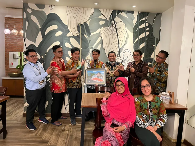 Rekan kerja berkumpul di ruang tunggu kantor memegang karikatur kelompok berbingkai.