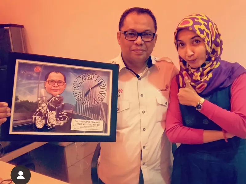 Seorang pria dan perempuan berhijab memegang karikatur berbingkai bertema jam.