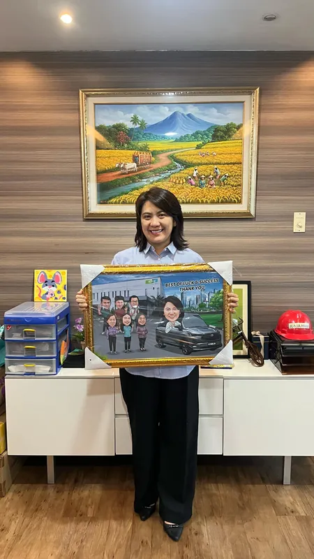 Seorang perempuan memegang karikatur kelompok berbingkai di ruang kerjanya.