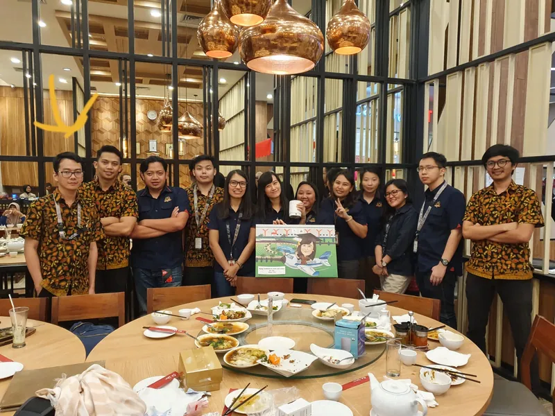 Rekan kerja berkumpul di restoran memegang karikatur kelompok berbingkai.