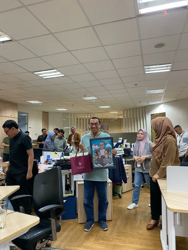 Rekan kerja berkumpul di ruang kerja memegang karikatur kelompok berbingkai.
