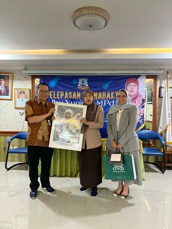 Penyerahan karikatur berbingkai pada acara pelepasan di ruang kantor.