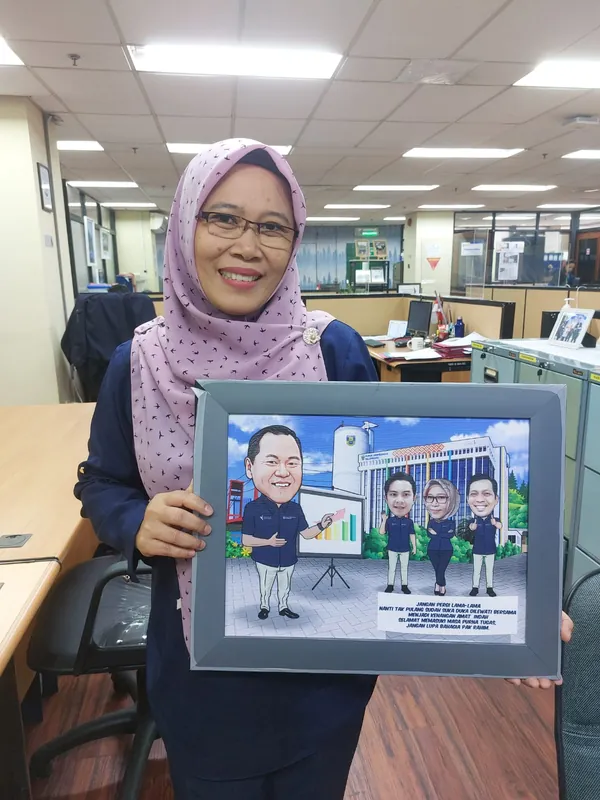 Perempuan berhijab memegang karikatur kelompok berbingkai di ruang kerja.