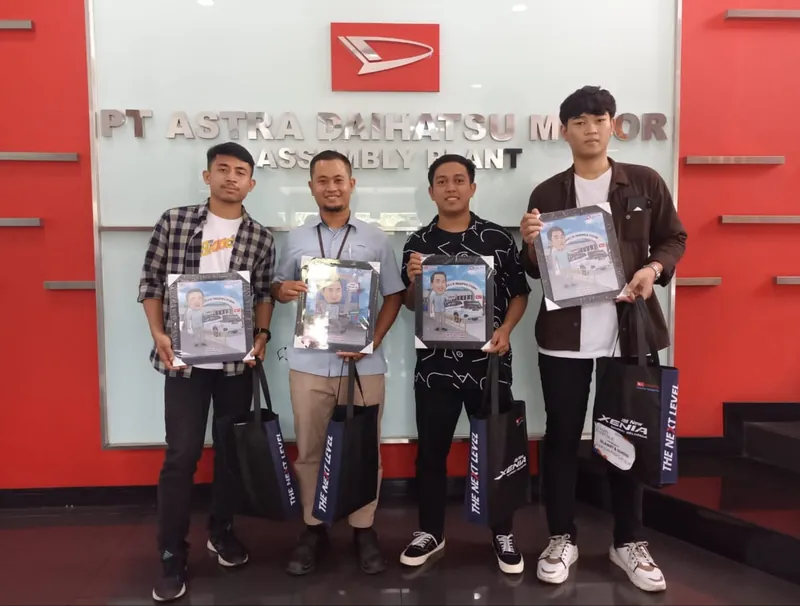 Empat karyawan memegang karikatur berbingkai masing-masing di pabrik Astra Daihatsu Motor.