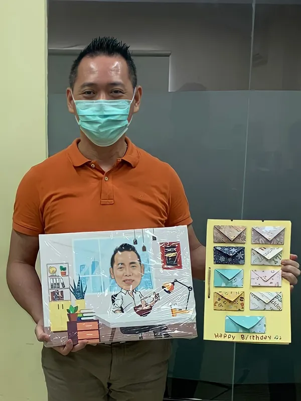 Seorang pria memegang karikatur berbingkai bertema kantor pos dan surat.