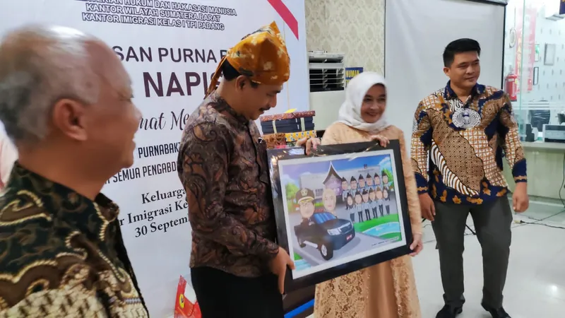 Penyerahan karikatur berbingkai pada acara pelepasan purna bakti di kantor pemerintah.