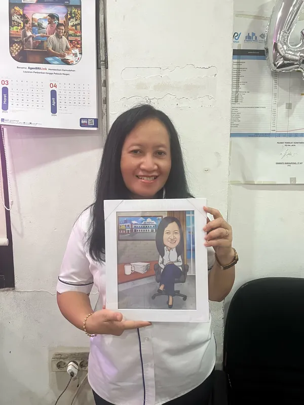 Seorang perempuan memegang karikatur berbingkai di ruang kerjanya.
