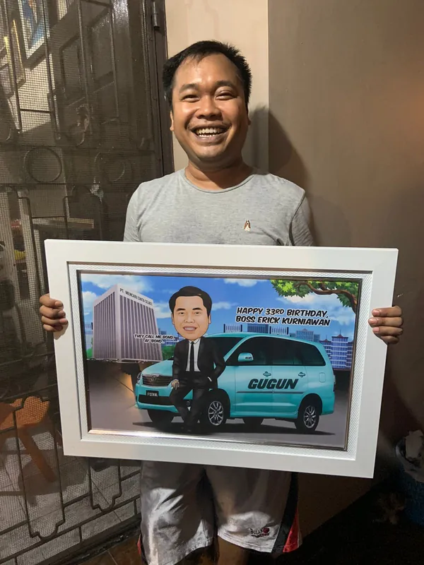 Seorang pria memegang karikatur berbingkai bertema mobil.
