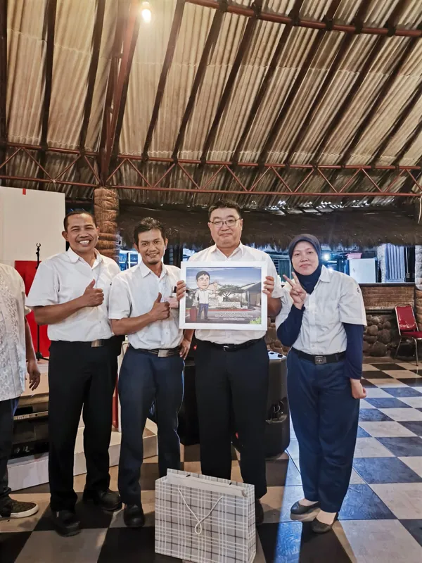 Empat pegawai memegang karikatur berbingkai di lobi kantor.