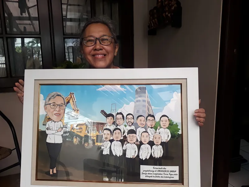 Seorang pria memegang karikatur kelompok berbingkai besar bertema konstruksi.