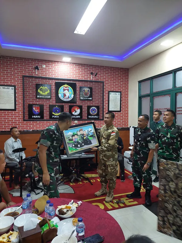 Anggota TNI memperlihatkan karikatur kelompok berbingkai di ruang acara.