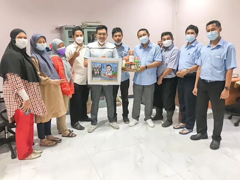 Rekan kerja berbaris di lobi kantor memegang karikatur kelompok berbingkai.