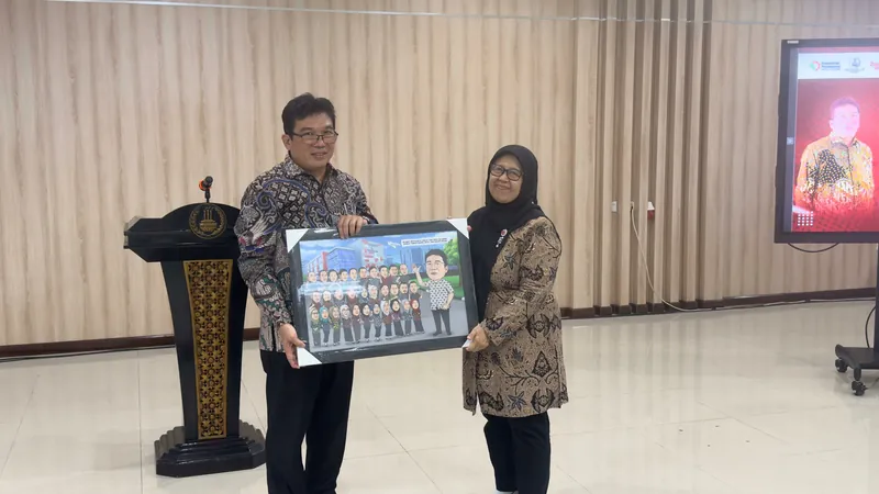 Dua orang memegang karikatur kelompok berbingkai di ruang aula.