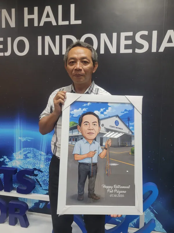 Seorang pria memegang karikatur berbingkai di depan panggung town hall kantor.