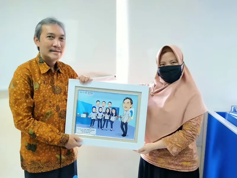 Seorang pria dan perempuan berhijab memegang karikatur berbingkai bertema mobil.