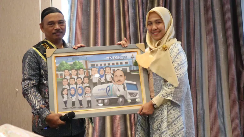 Seorang pria dan perempuan berhijab memegang karikatur kelompok berbingkai.