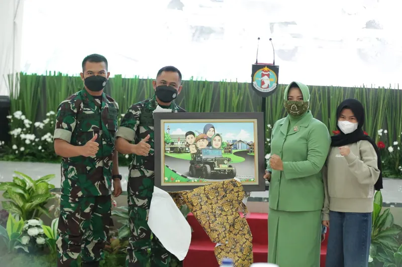 Anggota TNI dan keluarganya memegang karikatur berbingkai di ruang acara.