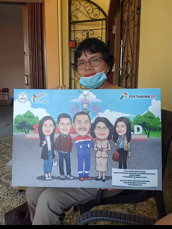 Karikatur keluarga berbingkai bertema Pertamina dipegang di ruang tamu.