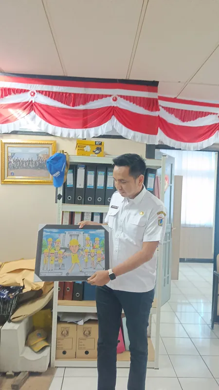 Seorang pria memegang karikatur kelompok berbingkai di ruang kerja.