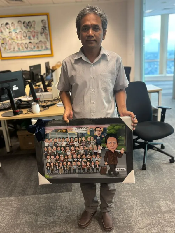 Seorang pria memegang karikatur kelompok berbingkai di ruang kerjanya.
