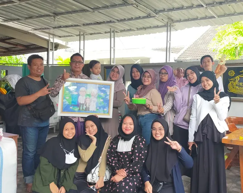 Rombongan perempuan berhijab berfoto memegang karikatur kelompok berbingkai.